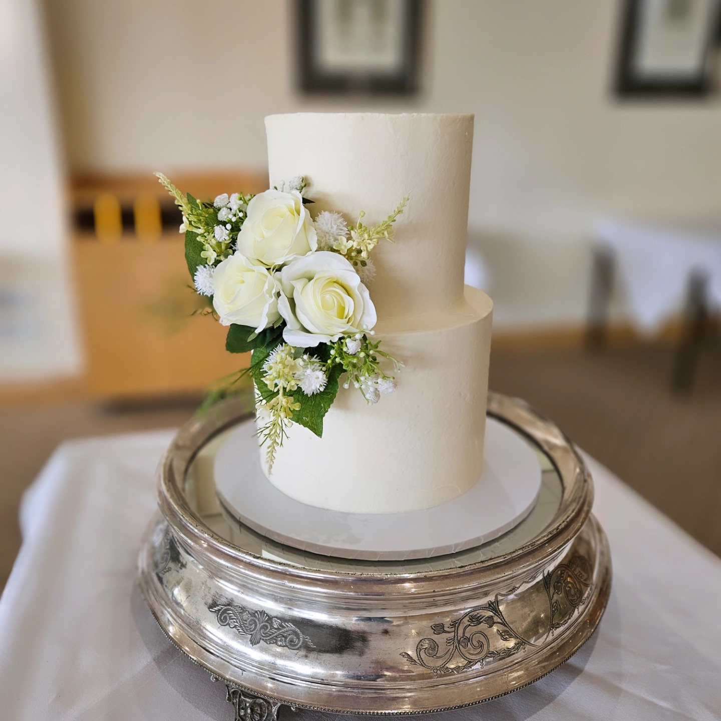 2 tier buttercream wedding cake with an artificial floral arrangement